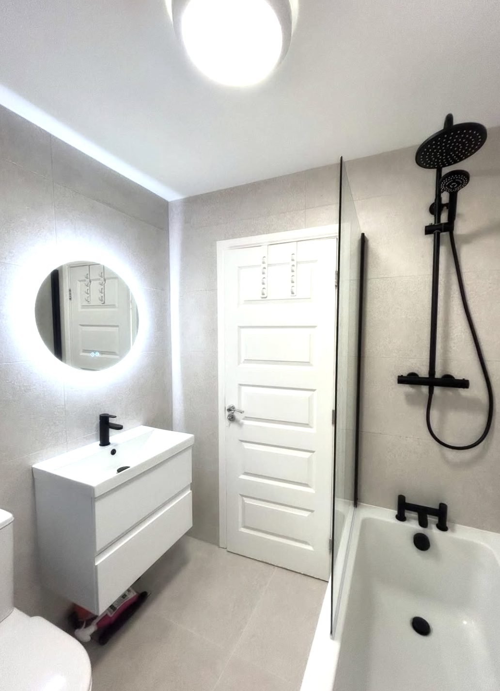 White bathroom refit with large format tiles and matt black brassware